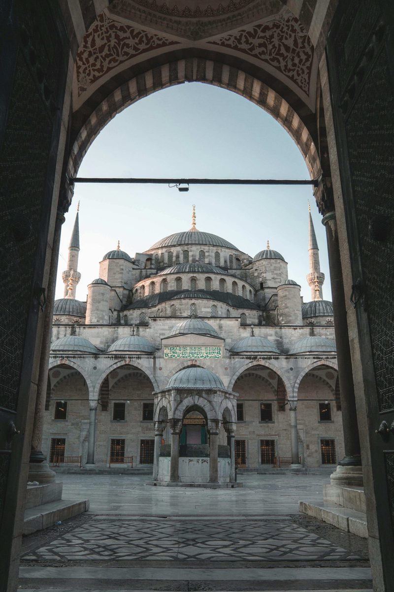 The Blue Mosque in Istanbul, framed by a stone archway in the courtyard